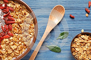 Smoothie bowl with goji berries and spoon on wooden table, closeup