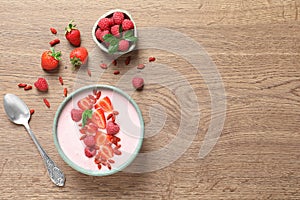 Smoothie bowl with goji berries and spoon on wooden table, flat lay