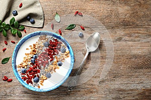 Smoothie bowl with goji berries and spoon on wooden table, flat lay