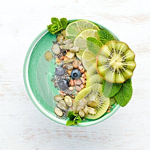 Smoothie bowl with green spirulina, kiwi, mint and pumpkin seeds. Breakfast. Top view.