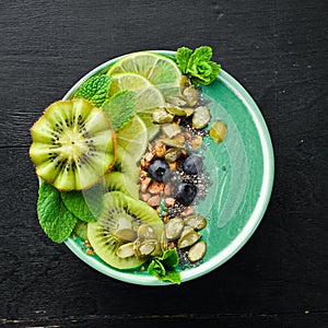 Smoothie bowl with green spirulina, kiwi, mint and pumpkin seeds. Breakfast. Top view.