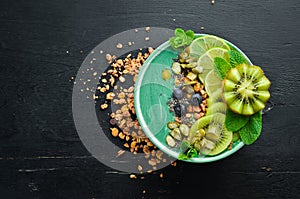 Smoothie bowl with green spirulina, kiwi, mint and pumpkin seeds. Breakfast. Top view.