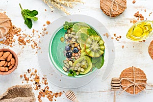 Smoothie bowl with green spirulina, kiwi, mint and pumpkin seeds. Breakfast. Top view.