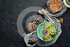 Smoothie bowl with green spirulina, kiwi, mint and pumpkin seeds. Breakfast. Top view.