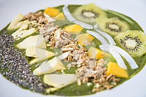 Smoothie bowl with kiwi, coconut, mango, pinapple, granola and chia seeds with green yogurt