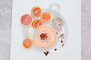 Smoothie bowl with slices or orange, lime or grapefruit, hempseed, spoon. Dry golden berry. Isolation on white background. Organic