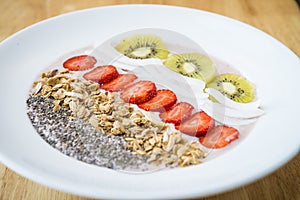 Smoothie bowl with strawberry, coconut, kiwi, granola and chia seeds