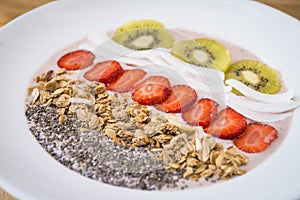 Smoothie bowl with strawberry, coconut, kiwi, granola and chia seeds