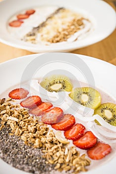 Smoothie bowl with strawberry, coconut, kiwi, granola and chia seeds