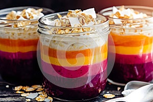 Smoothie jars with bright layers of fruit purÃÂ©e, oats, and coconut flakes