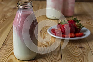 Smoothie with strawberry in bottles on wooden table