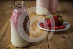 Smoothie with strawberry in bottles on wooden table