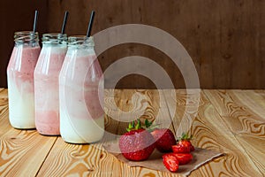 Smoothie with strawberry in bottles on wooden table