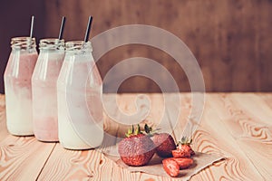 Smoothie with strawberry in bottles on wooden table