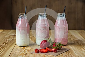 Smoothie with strawberry in bottles on wooden table