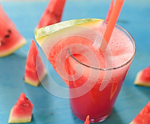 Smoothie with watermelon on a turquoise background in a glass with a slice of watermelon with copy space