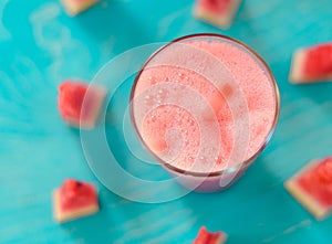 Smoothie with watermelon on a turquoise background in a glass with a slice of watermelon with copy space, top view