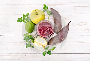 Smoothies with beet, apple, lemon, parsley in glass jars on a wooden background.