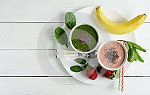 Smoothies made of banana and spinach and banana and strawberries on white wooden background.