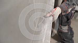 Plasterer using screeder smoothing putty plaster mortar on wall. Smoothing out putty on the wall. photo