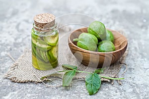 Smoothy unripe green walnuts and tincture of nuts in a transparent jar with a cork lid on an old vintage table. Leaves