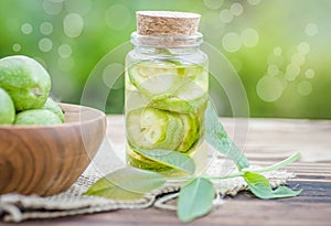 Smoothy unripe green walnuts and tincture of nuts in a transparent jar with a cork lid on an old vintage table. Leaves