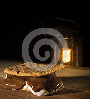 Smore on a wood surface with camping lantern behind