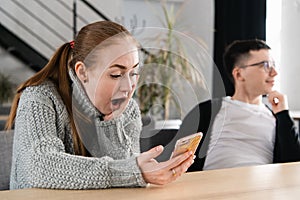 SMS. Closeup portrait funny shocked anxious scared young girl looking at phone seeing bad news photos message with