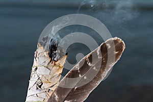 Smudging Ritual using burning thick leafy bundle of White Sage Grade A barred Turkey Smudging Feather on the beach at sunrise