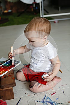 Smutty kid paints eggs on light background, photo