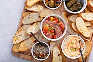 Snack board with baguette and dips and appetizers, roasted tomatoes, olives and pimento cheese