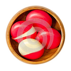 Snack cheese disks in red wax encasements, edam slices in wooden bowl