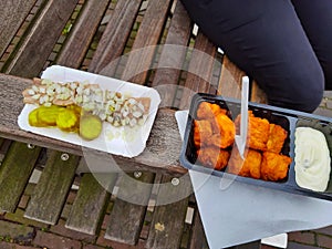 Snack on a Dutch wooden bench with fresh herring with onions and cucumbers and fried cod patties