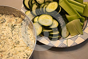 Snack of fresh spinich dip near plate of green vegetables on table