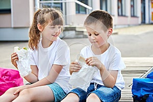 Snack during lessons. Happy children are eating breakfast in the schoolyard. Meals for students during lessons