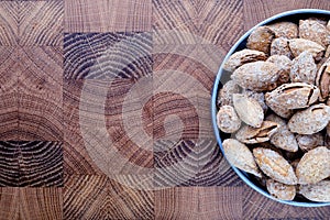 snack salted almonds in shell in metal plate on wooden chef's Board top view