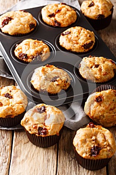 Snack savory muffins with sun-dried tomatoes and cheddar cheese close-up in a baking dish. vertical