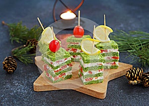 Snack, savoury spinach biscuit sandwices or canapes layered with cream cheese and salted salmon in Christmas and New Year style on