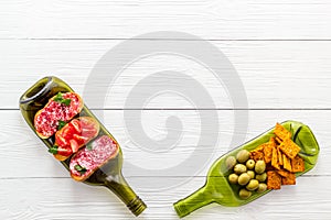 Snack set on wine bottles on white wooden desk from above copy space