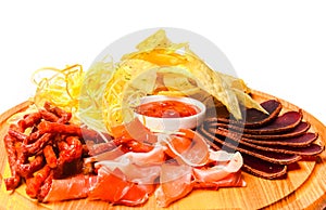 Snack to beer on a wooden board. Basturma, dried meat, dried squid, chips isolated on white background.