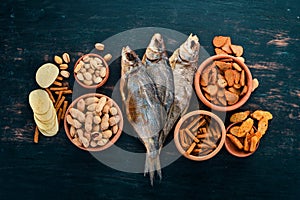 Snacks for beer. Salted crackers, Dried Fish, Chips, Nuts, Peanuts, Pistachios. On a wooden background.