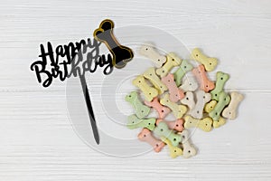 Snacks, black topper Happy birthday for dogs on white wooden table. Set of accessories for pets on wood. Close up.