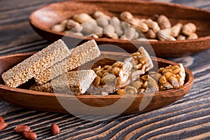 Snacks - mix of energy bars with peanut, sesame and sunflower seeds on a wooden background. Nuts in caramel, honey Snack food. Unh