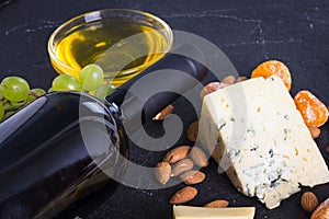 Snacks with wine - bottle, various types of cheeses, figs, nuts, honey, grapes