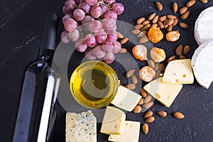 Snacks with wine - bottle, various types of cheeses, figs, nuts, honey, grapes