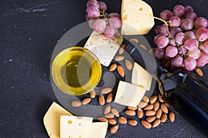 Snacks with wine - bottle, various types of cheeses, figs, nuts, honey, grapes