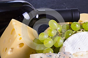 Snacks with wine - bottle, various types of cheeses, figs, nuts, honey, grapes