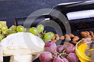 Snacks with wine - bottle, various types of cheeses, figs, nuts, honey, grapes
