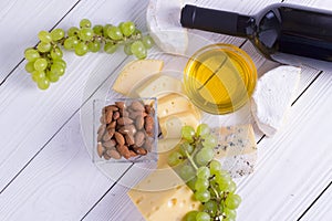 Snacks with wine - bottle, various types of cheeses, figs, nuts, honey, grapes