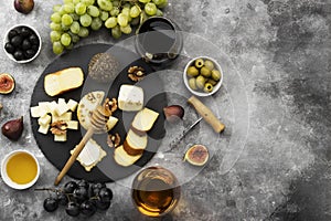 Snacks with wine - various types of cheeses, figs, nuts, honey, grapes on a gray background. Top view, copy space. Food background